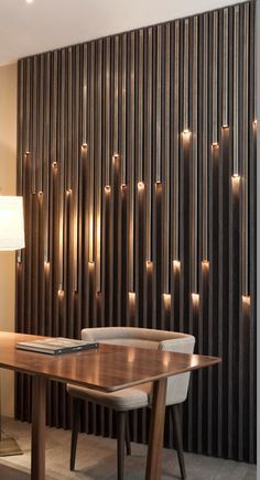 a wooden table sitting in front of a wall with lights on it and a lamp next to it