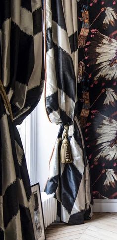 black and white curtains with gold tassels in front of a floral wallpaper