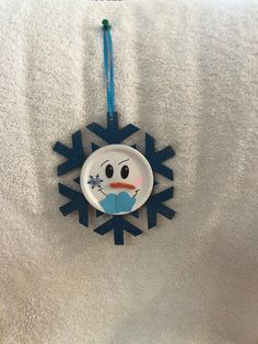 a snowflake shaped ornament hanging from a blue ribbon on a white blanket