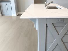 a white kitchen island with a sink and cupboards in the backround area