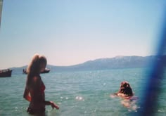 a woman standing in the water next to a dog