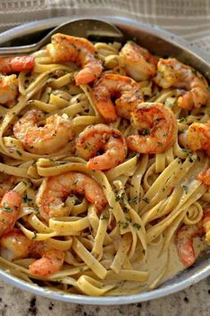 a bowl filled with pasta and shrimp on top of a table