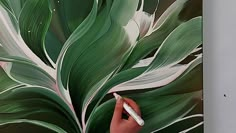 someone is painting a large green plant with white leaves