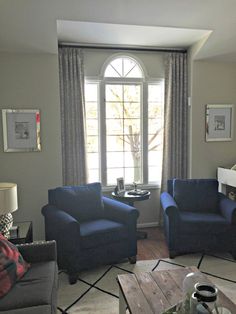 a living room with two blue chairs and a coffee table in front of a window