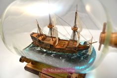 a model ship in a glass ball on top of a wooden base with water inside