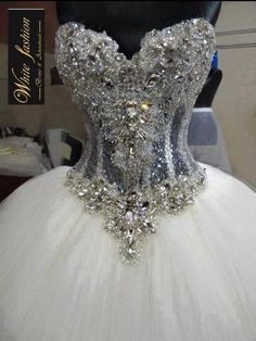 a white wedding dress with silver and crystal stones on the bust, is displayed in front of a mannequin