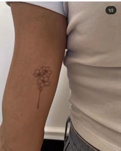 a woman's arm with a small flower tattoo on the left side of her arm