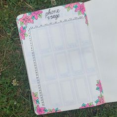 an open notebook sitting on top of grass with pink flowers in the pages and numbers