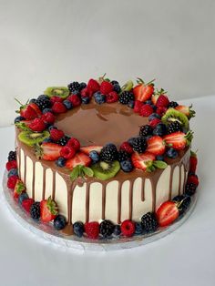 a chocolate cake topped with fresh fruit and drizzled in chocolate icing