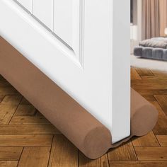 a close up of a door handle on a wooden floor with a bed in the background