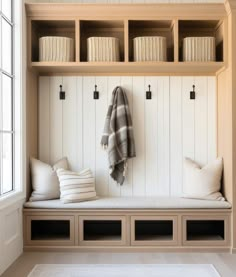 a white bench with some pillows and blankets on it next to a window in a room