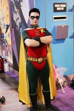 a man dressed as batman standing in front of a blue wall