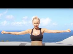 a woman with her arms outstretched standing on a balcony overlooking the ocean and blue sky