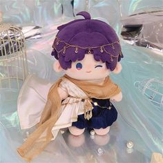 a small doll with purple hair and blue eyes sitting on a table next to a birdcage