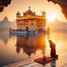 a man standing in front of a body of water with a golden building behind him