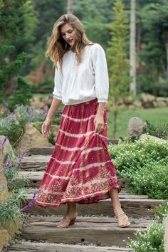 India's Dinesh Singh creates an enchanting, flowy skirt expertly tie-dyed by hand in a rich crimson shade. It is adorned with stunning floral and leaf-themed embroidery created with golden-hued beads and sequins along the hem. The fully lined, long cotton skirt has a hint of golden lurex and scattered beading for shimmer. The front waist is fixed for a polished look while the back features an elasticized waistband for a comfortable fit. Long Cotton Skirt, Layering Jacket, Embellished Clothing, Embellished Skirt, Poncho Shawl, Tie Dye Outfits, Beautiful Kimonos, Embroidered Clothes, Red Outfit