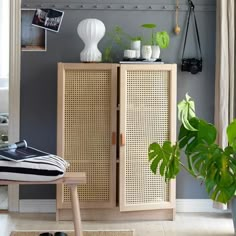 a living room with a plant on top of a wooden cabinet and pictures hanging on the wall