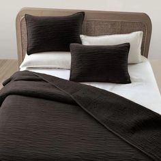 a bed with black and white pillows on top of it