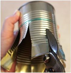 a person holding a can with some metal parts on it's side and the bottom part missing