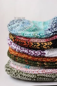 a stack of knitted headbands sitting on top of each other in different colors