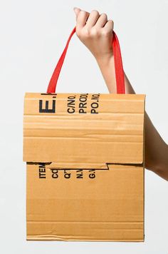 a person holding up a cardboard bag with numbers and measurements printed on the side, in front of a white background