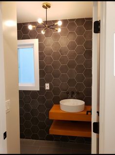 a bathroom with hexagonal tiles on the wall and a round sink in the center