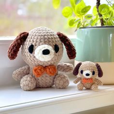 two crocheted dogs sitting on a window sill next to a potted plant