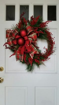 a red and green christmas wreath on a white door