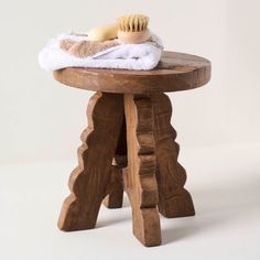 a wooden stool with a white towel on top of it and a hair brush sitting on top of it