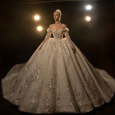 a woman in a white wedding dress standing on a black surface with lights behind her