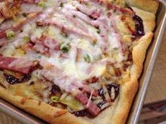 a pizza sitting on top of a pan covered in cheese and toppings with meat