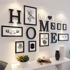 a white table topped with pictures and vases on top of it next to a wall