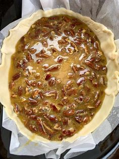 an uncooked pie sitting on top of a pan covered in pecan nuts