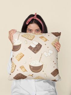 a woman holding up a pillow with coffee and cookies on it