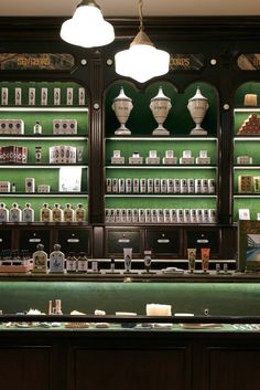 a store with green walls and shelves filled with different types of items on display behind the counter