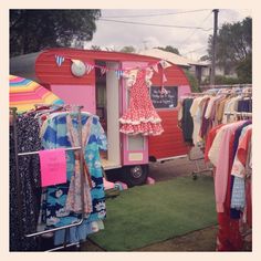 a small pink trailer with clothes hanging on it's sides and an umbrella in the background