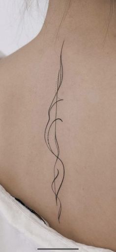 the back of a woman's neck with a vine tattoo on her left shoulder