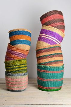 two colorful baskets sitting next to each other on top of a wooden table with white wall in the background