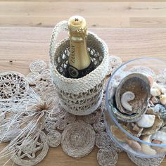 a bottle of wine sitting on top of a table next to shells and doily