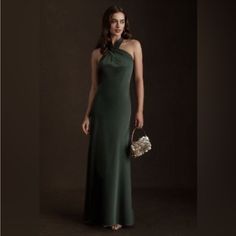 a woman in a long green dress holding a purse