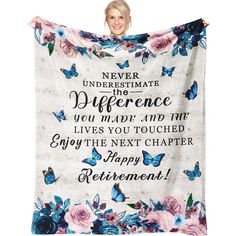 a woman holding up a blanket with flowers and butterflies on it that says never underestimi