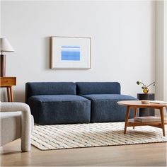 a living room with a blue couch and coffee table in front of a white wall