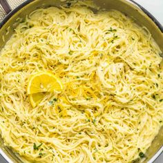 a pan filled with pasta and lemon wedges