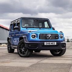 a blue mercedes g - class parked in front of a building