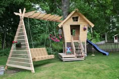 a wooden swing set with a tree house in the back ground and a slide on the other side