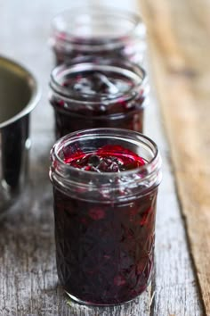 three jars filled with jam sitting on top of a wooden table