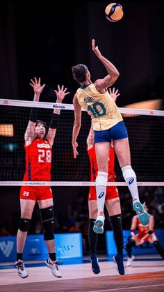 two volleyball players jumping up to hit the ball