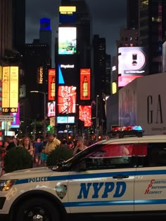 a nypd police car is parked in the middle of a busy city at night