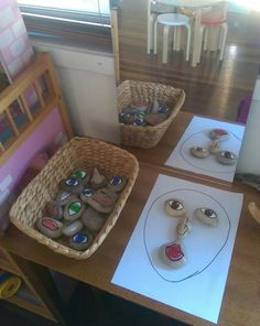 two baskets filled with rocks sitting on top of a table next to paper and markers