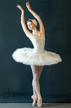 the ballerina is posing in her white tutu